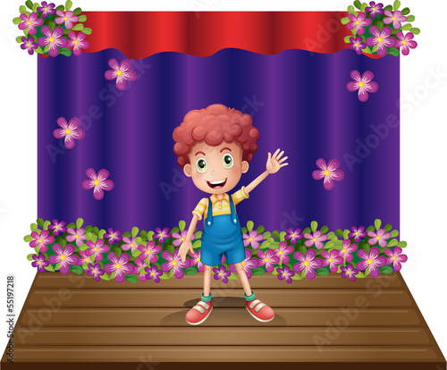 A stage with a young boy waving happily
