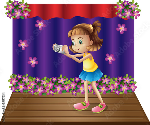 A stage with a young girl holding a camera