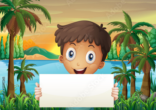 A young boy at the riverbank holding an empty signboard