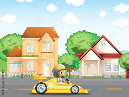 A boy in his racing car across the neighborhood