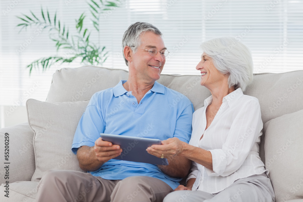 Couple using a tablet pc sitting on the couch Couple using a tablet pc sitting on the couch