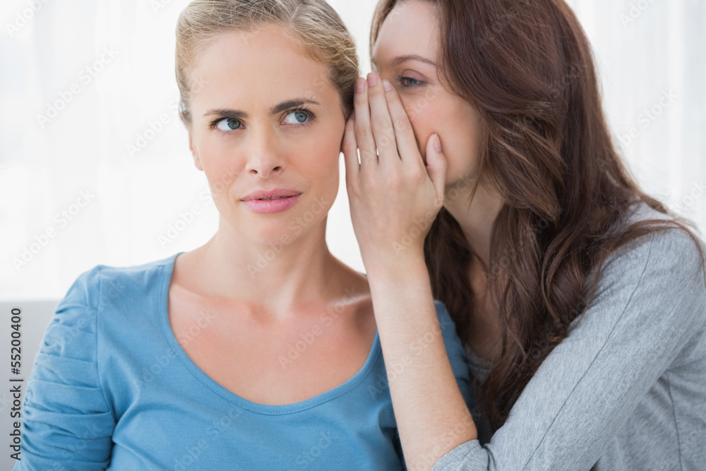 Blond woman hearing a secret from her friend Blond woman hearing a secret from her friend