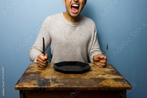 Fototapeta Hungry young man is screaming for his dinner