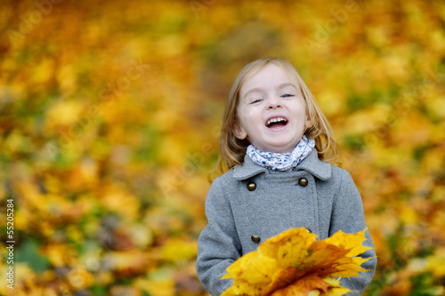 Adorable girl having fun on autumn day