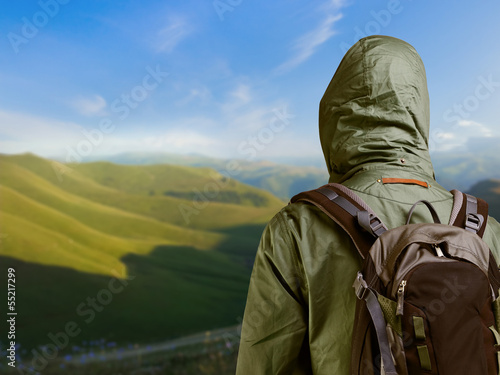 Hiker with backpack standing on top of a mountain and enjoying n