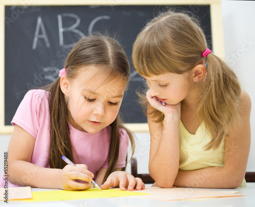 Little girls are writing using a pen