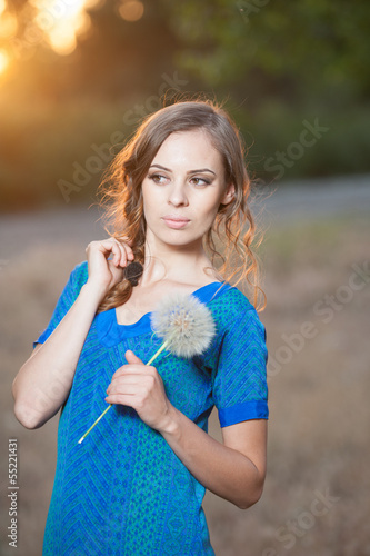girl with dandelion enjoying the summer sun outdoors in the park
