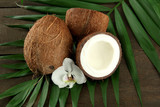 Coconuts with leaves and flower, on grey wooden background