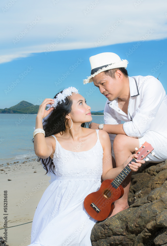 Couple sitting playing guitar in the beach