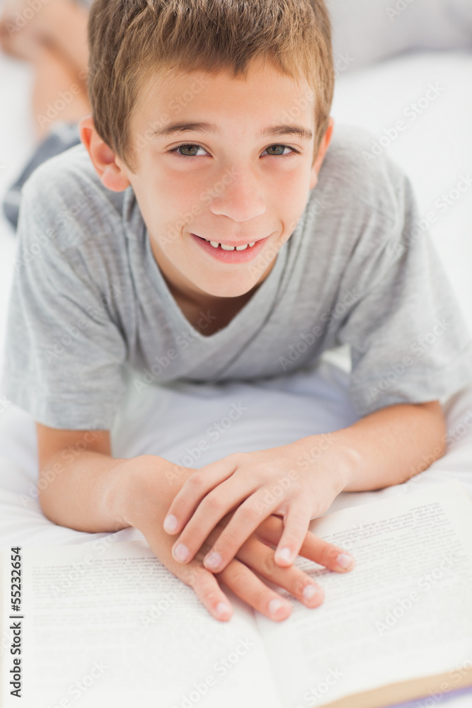 Happy little boy lying on bed reading book Happy little boy lying on bed reading book