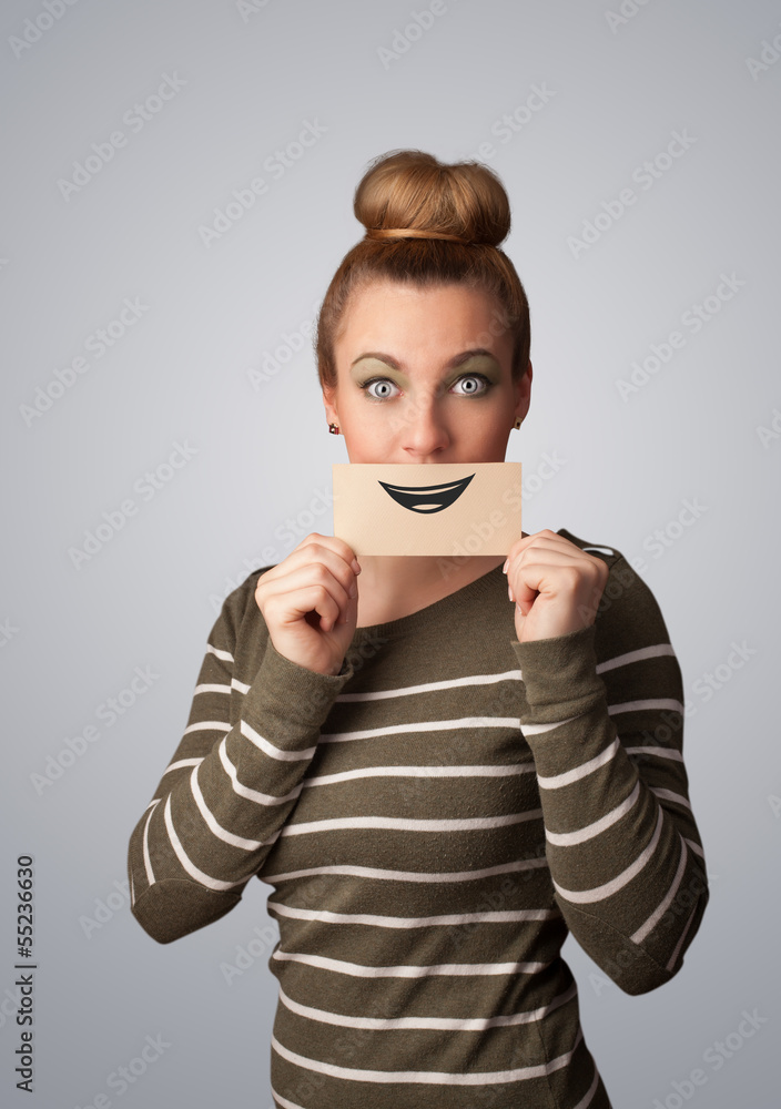 Happy pretty woman holding card with funny smiley Happy pretty woman holding card with funny smiley