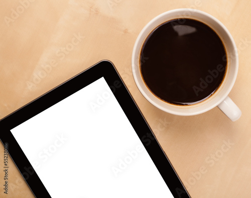 Tablet pc with empty space and a cup of coffee on a desk