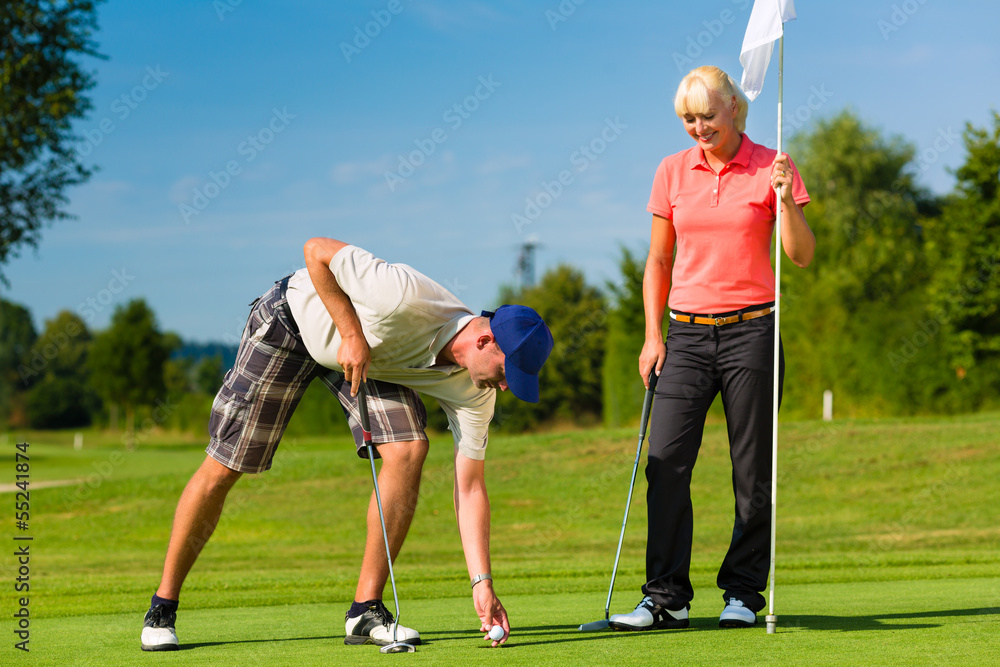 Young sportive couple playing golf on a course Young sportive couple playing golf on a course