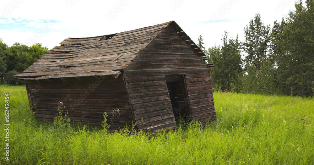 Old leaning farm shed in grassy field. Old leaning farm shed in grassy field.