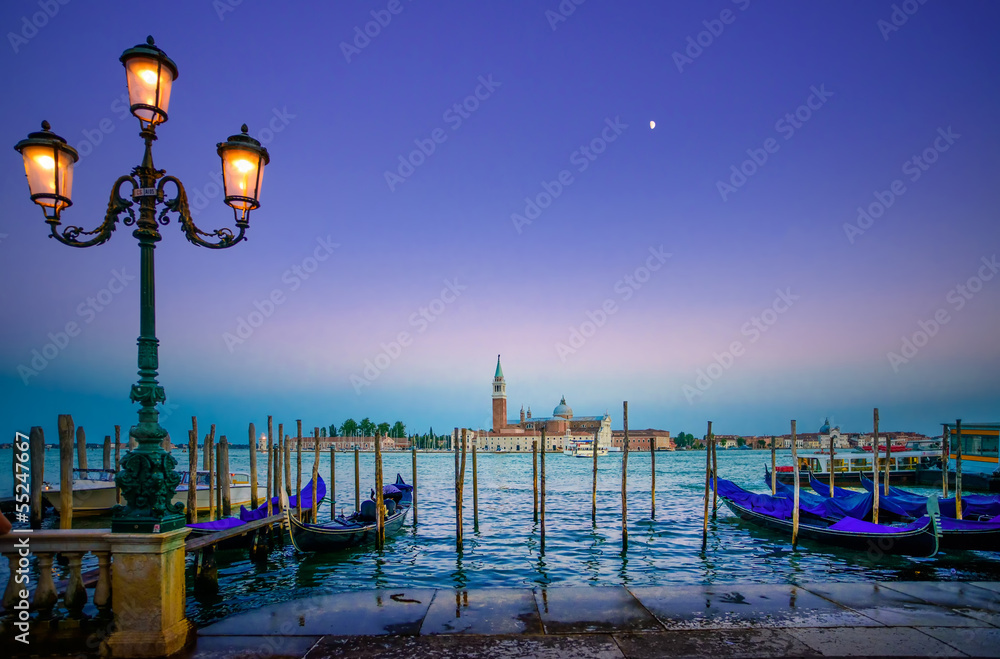 Venice, street lamp and gondolas on sunset and church. Italy