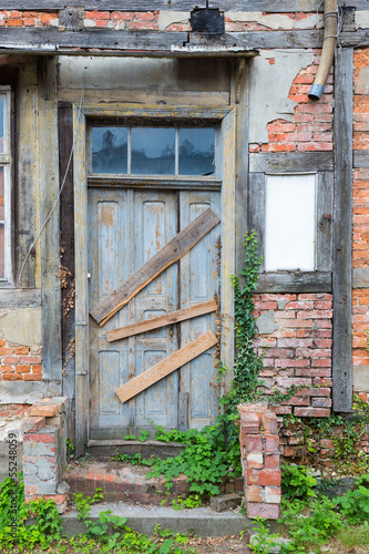 Obraz na plátně Old dilapidated door in masonry house front