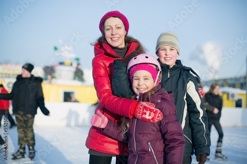 A mother with two children standing on outdoor rink