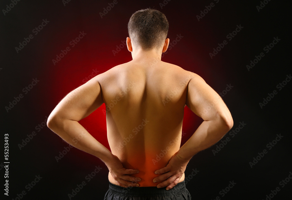 Lower back pain in man on dark background Lower back pain in man on dark background
