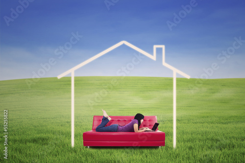 Asian female lying on sofa in dream house outdoor © Creativa Images