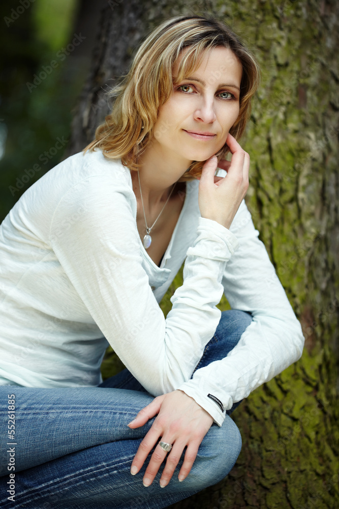 Portrait of smiling woman kneeling in a park Portrait of smiling woman kneeling in a park