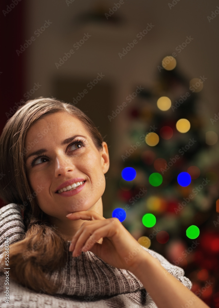 Portrait of thoughtful young woman near christmas tree Portrait of thoughtful young woman near christmas tree