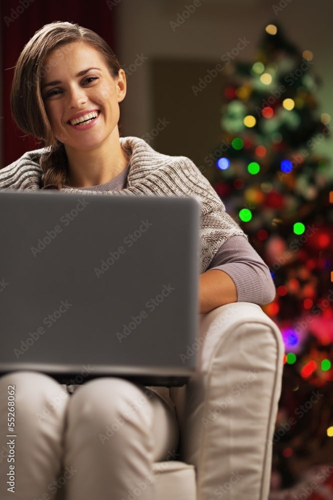 Happy young woman near christmas tree with laptop Happy young woman near christmas tree with laptop
