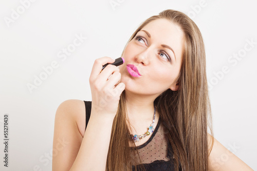 Cute blonde teenage girl applying pink lipstick