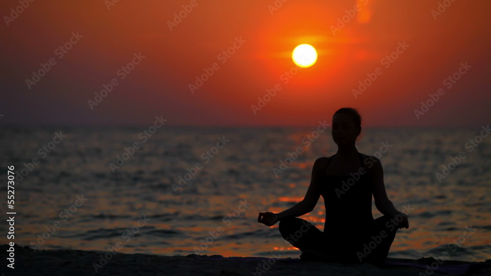 young woman is engaged in gymnastics at sea at sunrise young woman is engaged in gymnastics at sea at sunrise