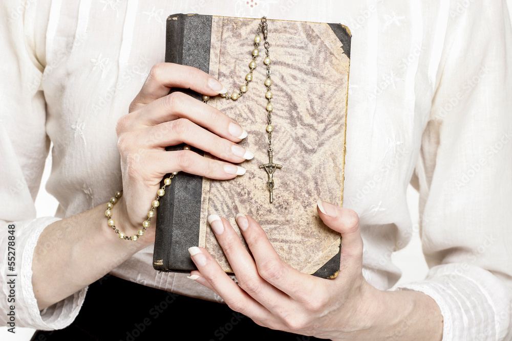 Holy Bible and white rosary in beautiful hands