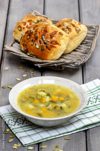 Vegetable soup on wooden table. Basket with fresh buns