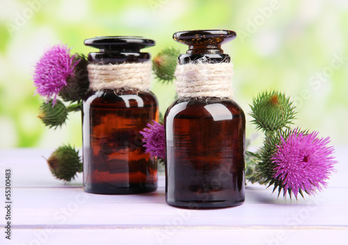 Medicine bottles with thistle flowers on nature background