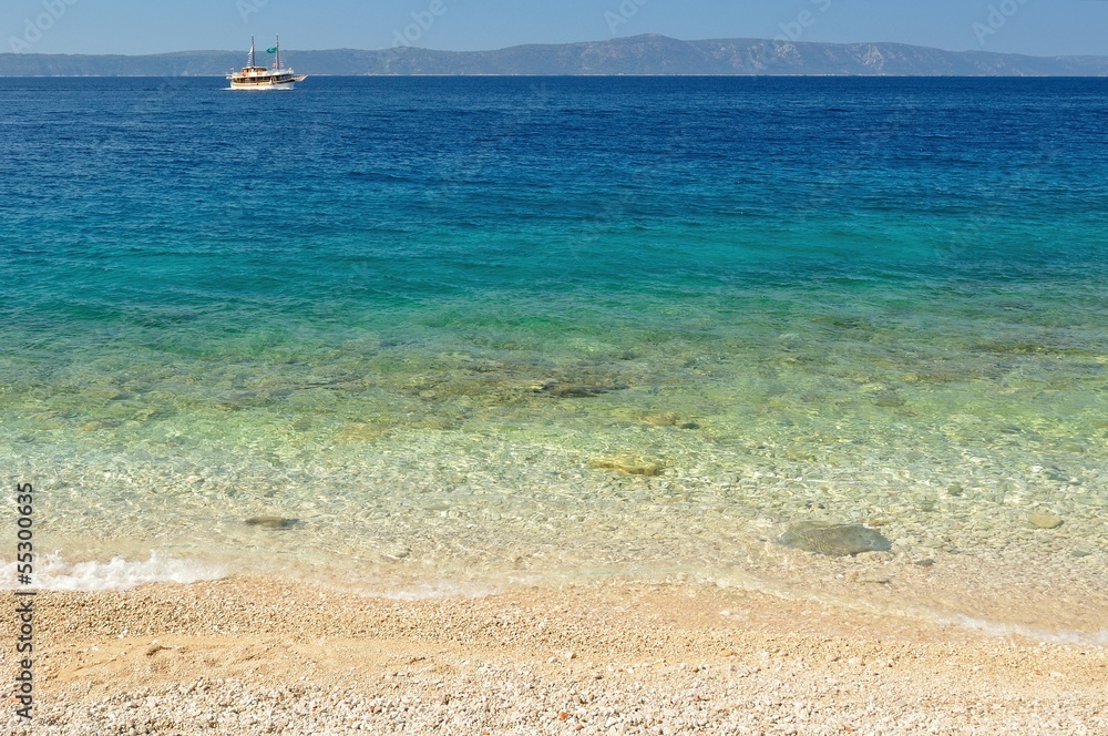Beautiful beach with ship and island Hvar in background Beautiful beach with ship and island Hvar in background