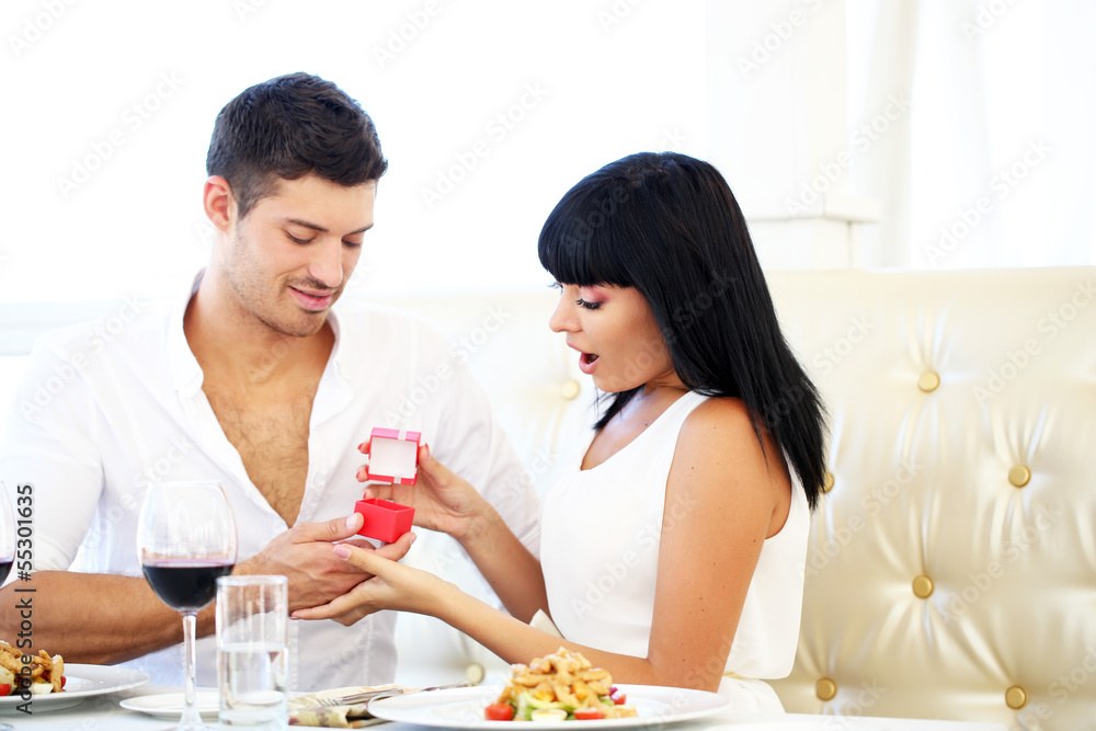 Man proposing and holding up an engagement ring his woman over