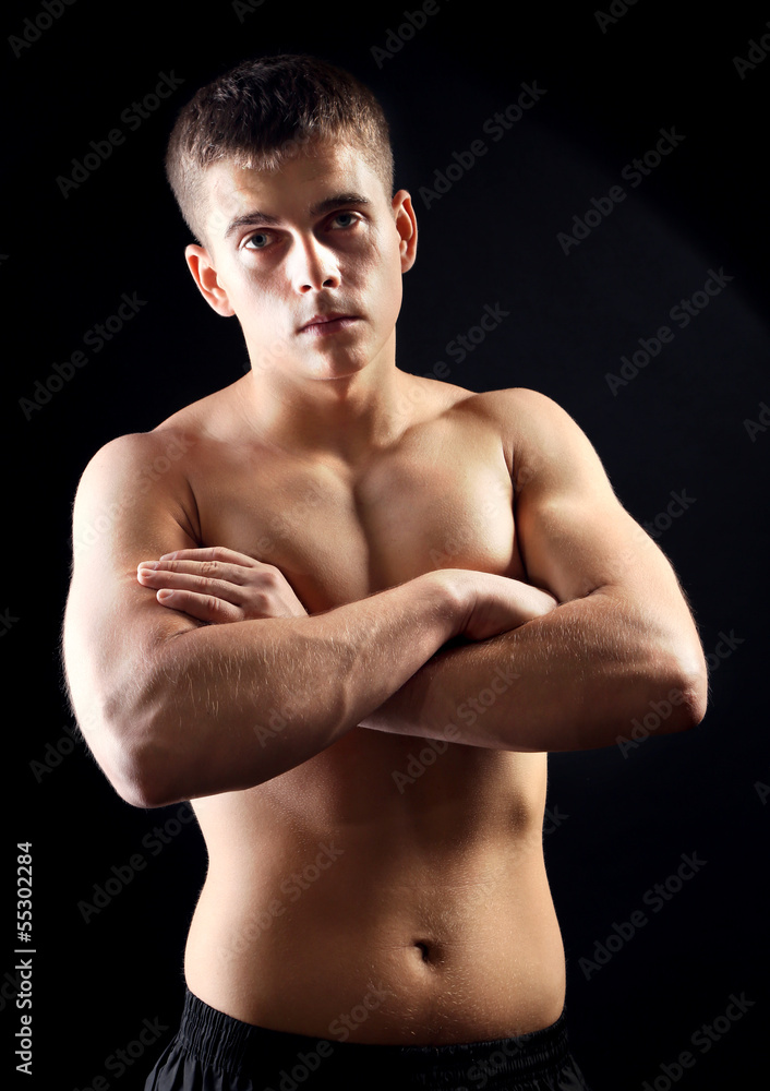 Fototapeta premium Handsome young muscular sportsman, on dark background
