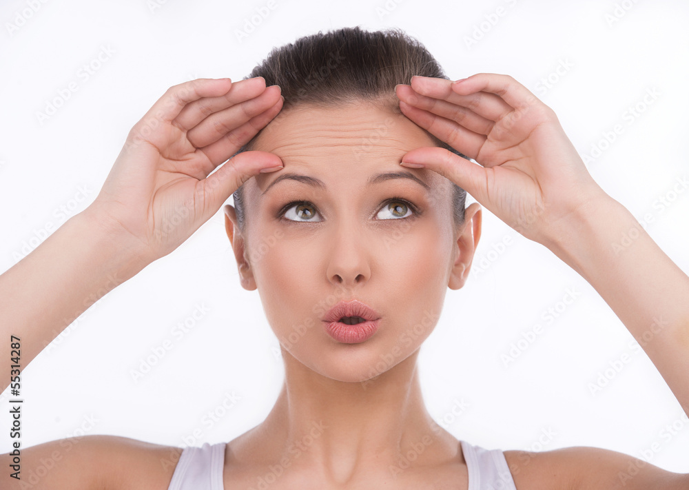 Forehead wrinkles. Surprised young woman touching her forehead a Forehead wrinkles. Surprised young woman touching her forehead a