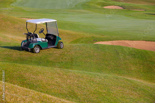 Green golf cart on the empty golf course