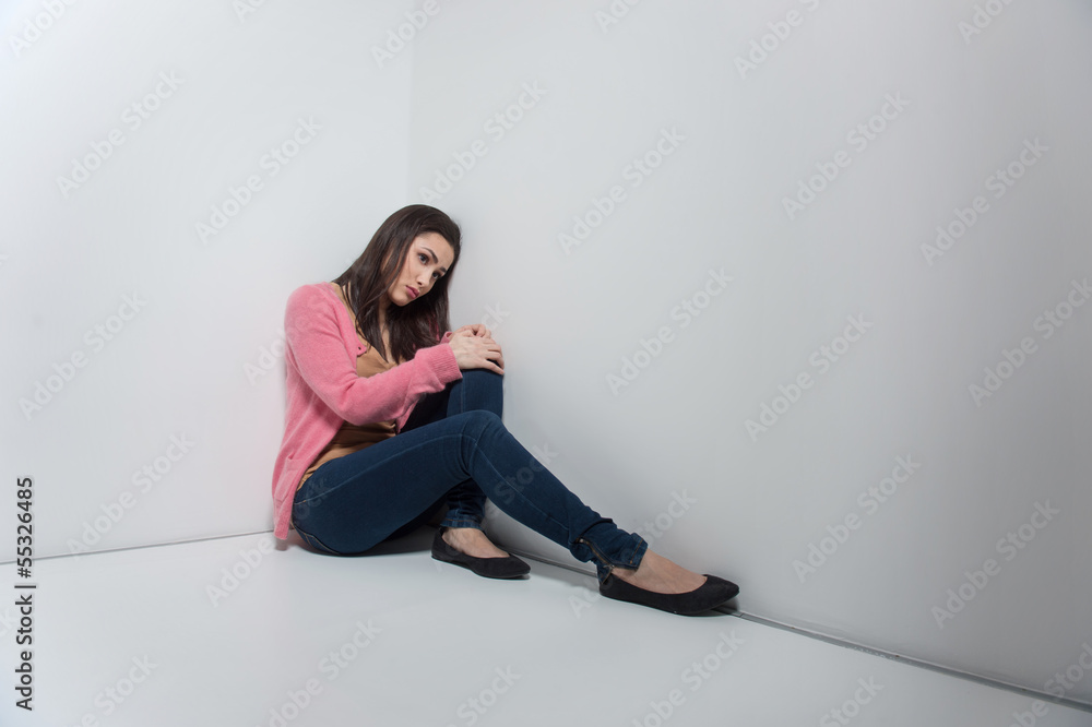 Loneliness. Depressed young woman sitting on the floor and leani Loneliness. Depressed young woman sitting on the floor and leani