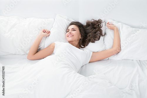 young woman lying on the white linen in bed