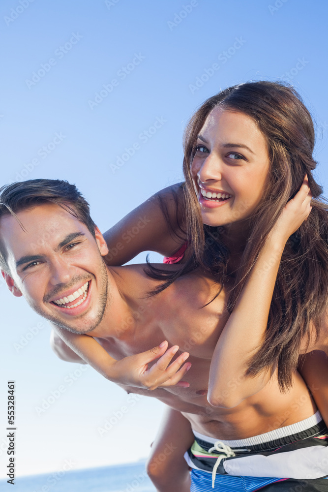 Cheerful handsome man carrying his girlfriend on his back Cheerful handsome man carrying his girlfriend on his back