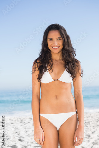 Smiling pretty brunette posing in white bikini