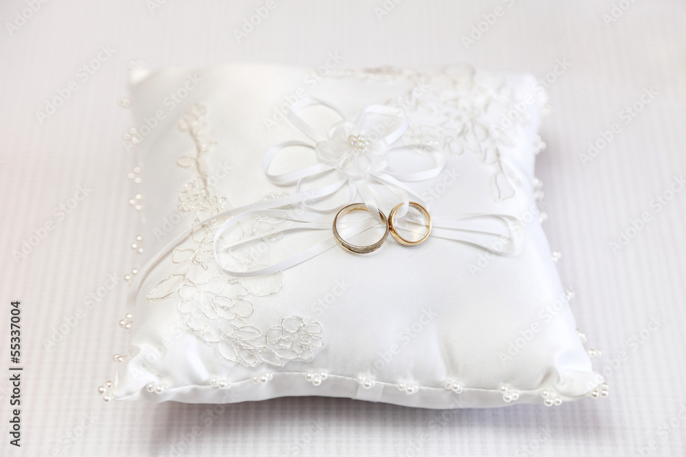 Obrączki ślubne na białej ozdobnej poduszce. Stock Photo | Adobe Stock