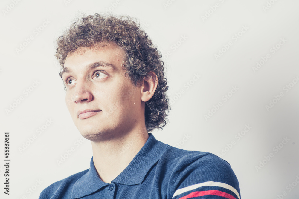 Fototapeta premium Curly haired young man on gray background with pensive