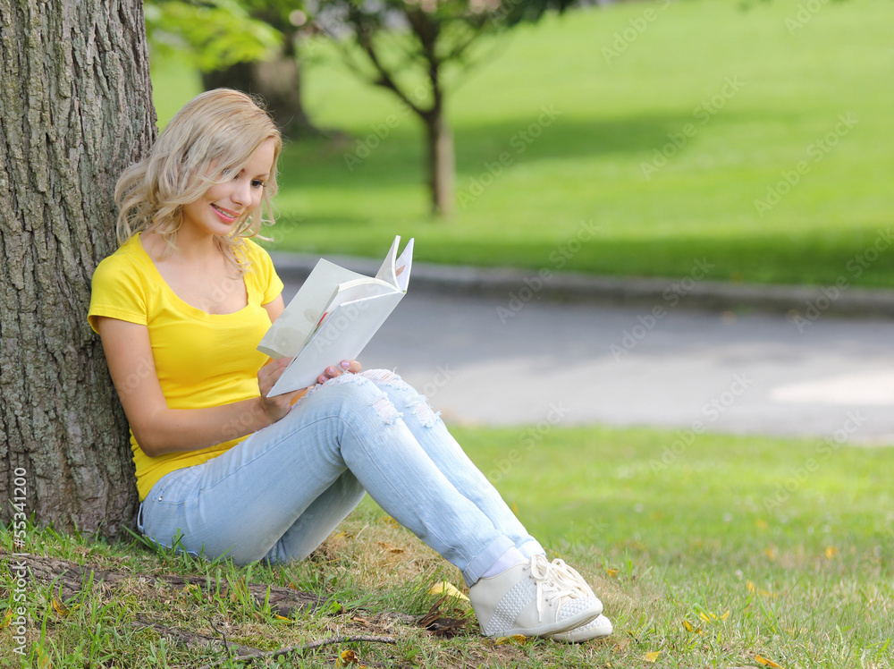 Girl reading book. beautiful blonde with book sitting on grass Girl reading book. beautiful blonde with book sitting on grass