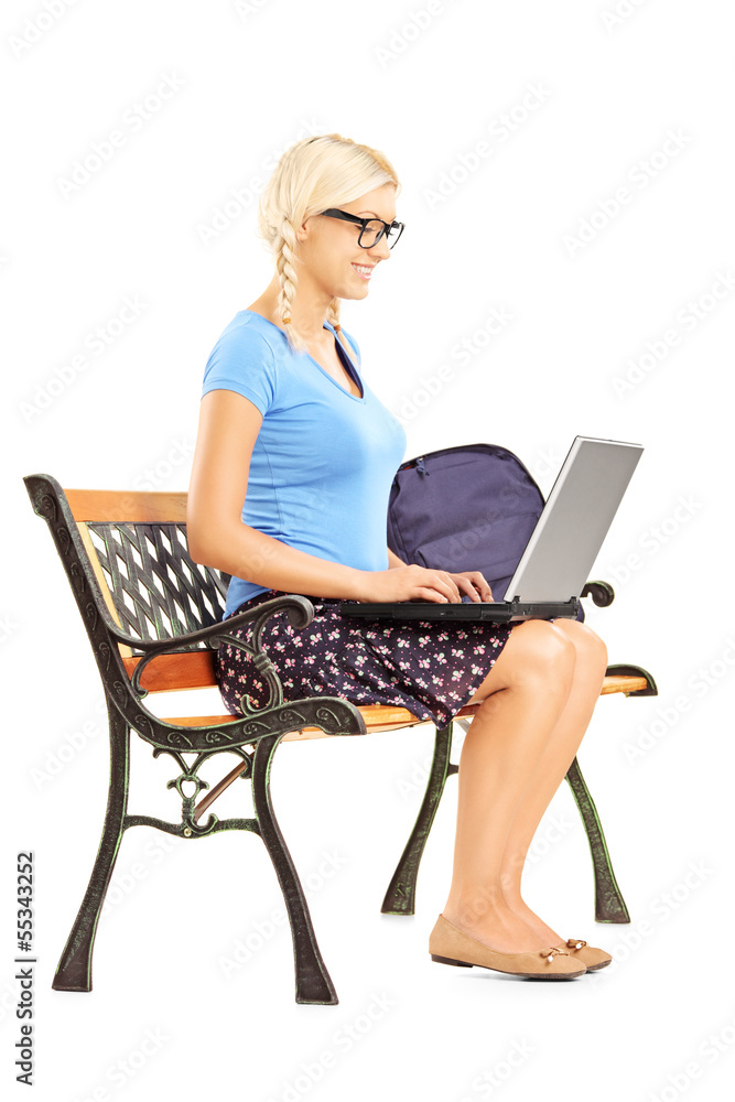 Smiling blond female student sitting on a bench and working Smiling blond female student sitting on a bench and working