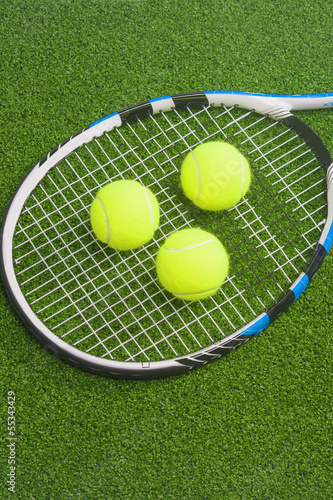 Tennis concept: racket with balls lies on green grass court