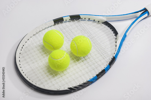 Tennis racket and three green balls on white background