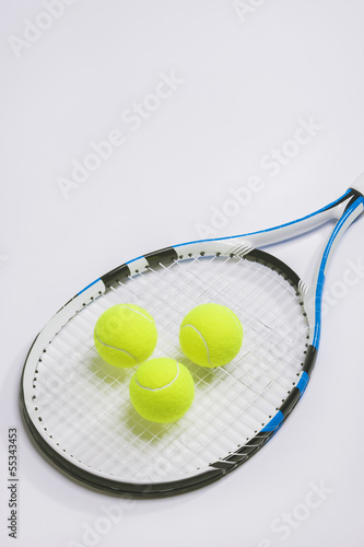 Tennis racket and three green balls on white background.