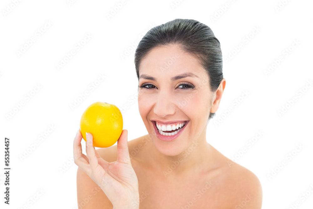 Smiling brunette holding an orange and looking at camera Smiling brunette holding an orange and looking at camera
