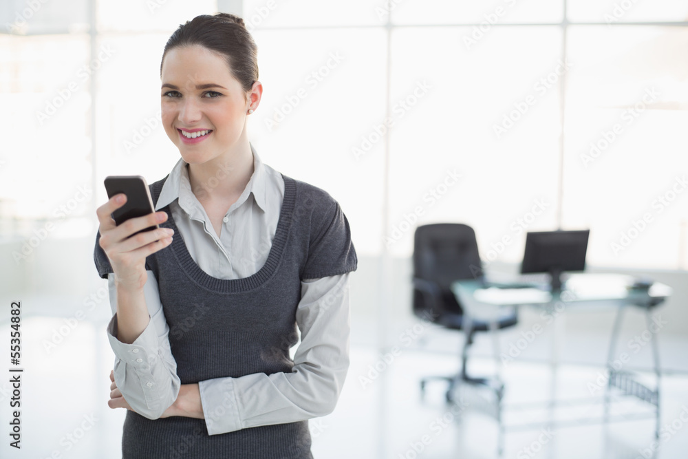 Smiling businesswoman holding her smartphone posing Smiling businesswoman holding her smartphone posing