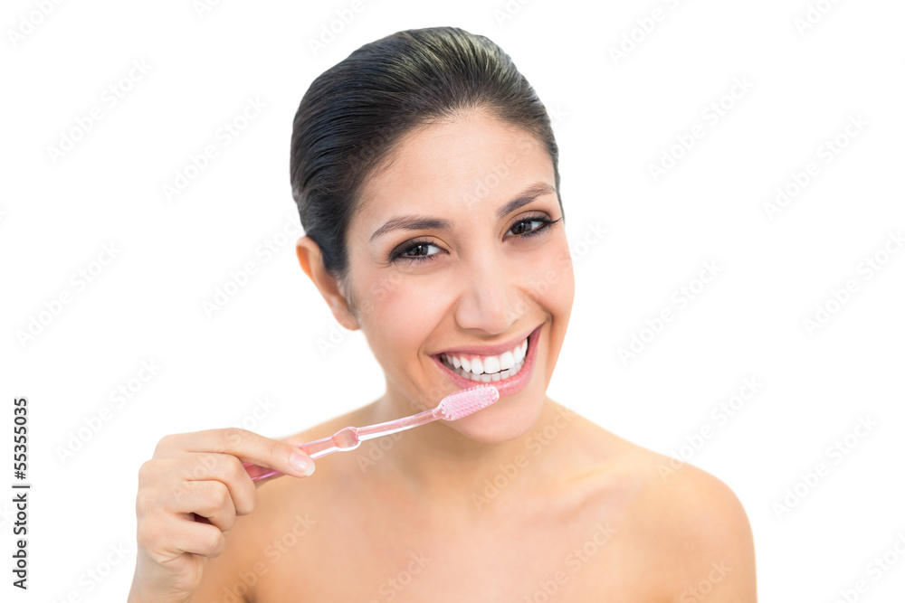Brunette brushing her teeth and smiling at camera Brunette brushing her teeth and smiling at camera